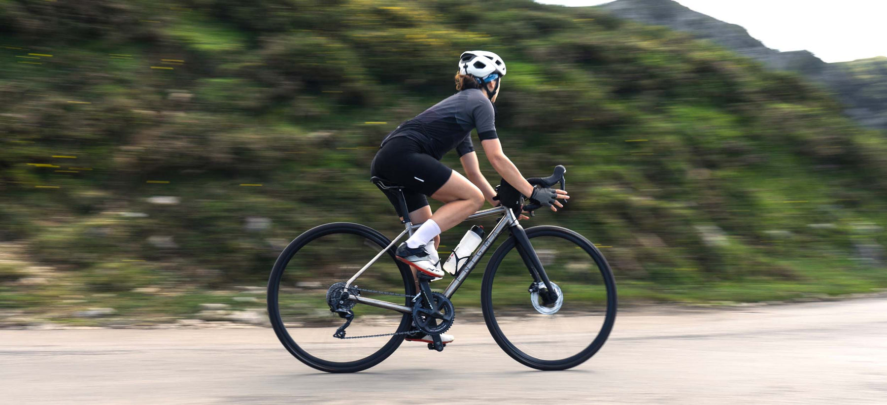 Rider on an Enigma titanium all road bike riding on tarmac.