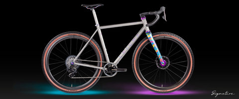 Full side view of Enigma Esker titanium gravel bike with custom-painted fork, purple Chris King components, Pirelli Cinturato tyres, and subtle underlighting on a black background, labelled Signature.