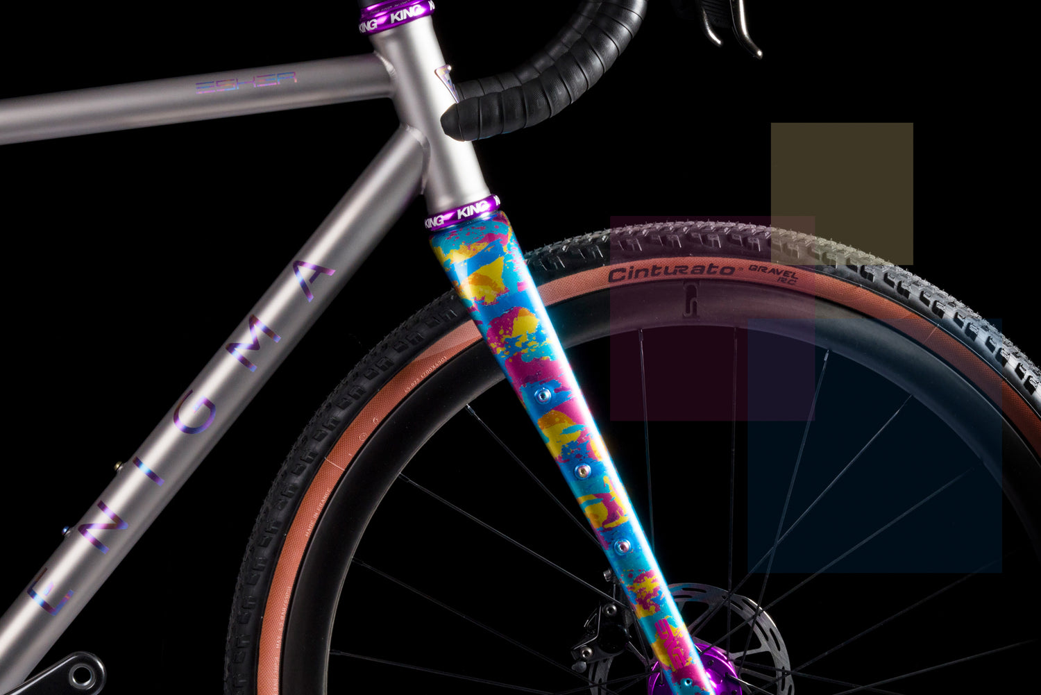 Close side view of Enigma titanium gravel bike highlighting the custom-painted fork in blue, yellow, and magenta, purple Chris King components, and Pirelli Cinturato tyres against a black background.