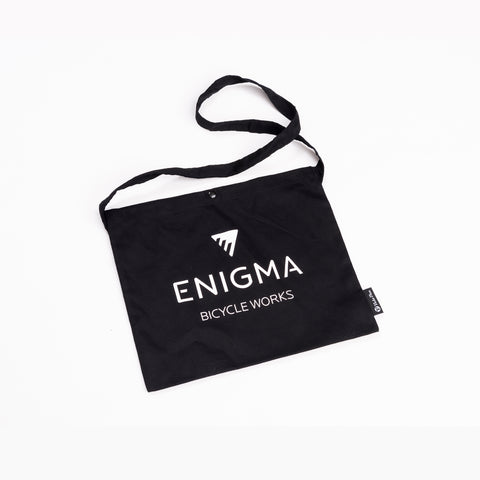 A black cotton tote bag with a logo printed on the front, featuring a handle at the top.