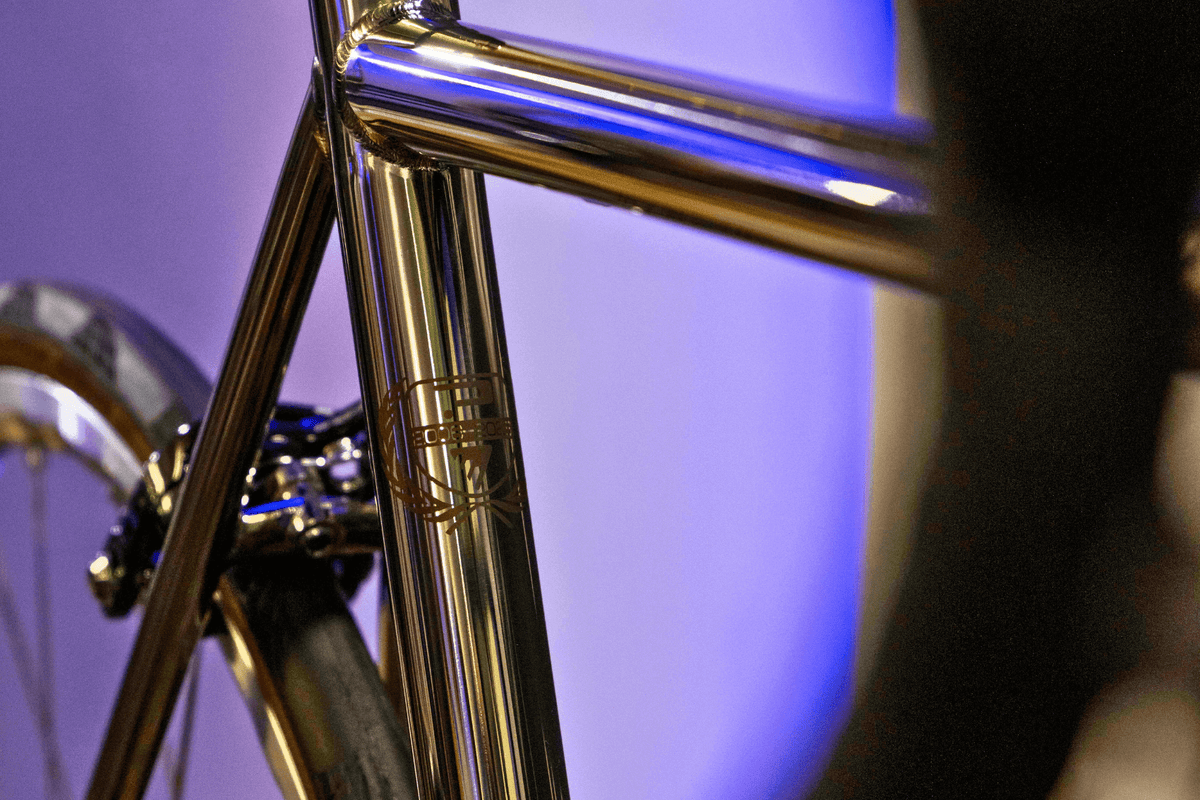 Close-up of Enigma titanium bike frame with a mirror polish and engraved seat tube at Rouleur Live 2025