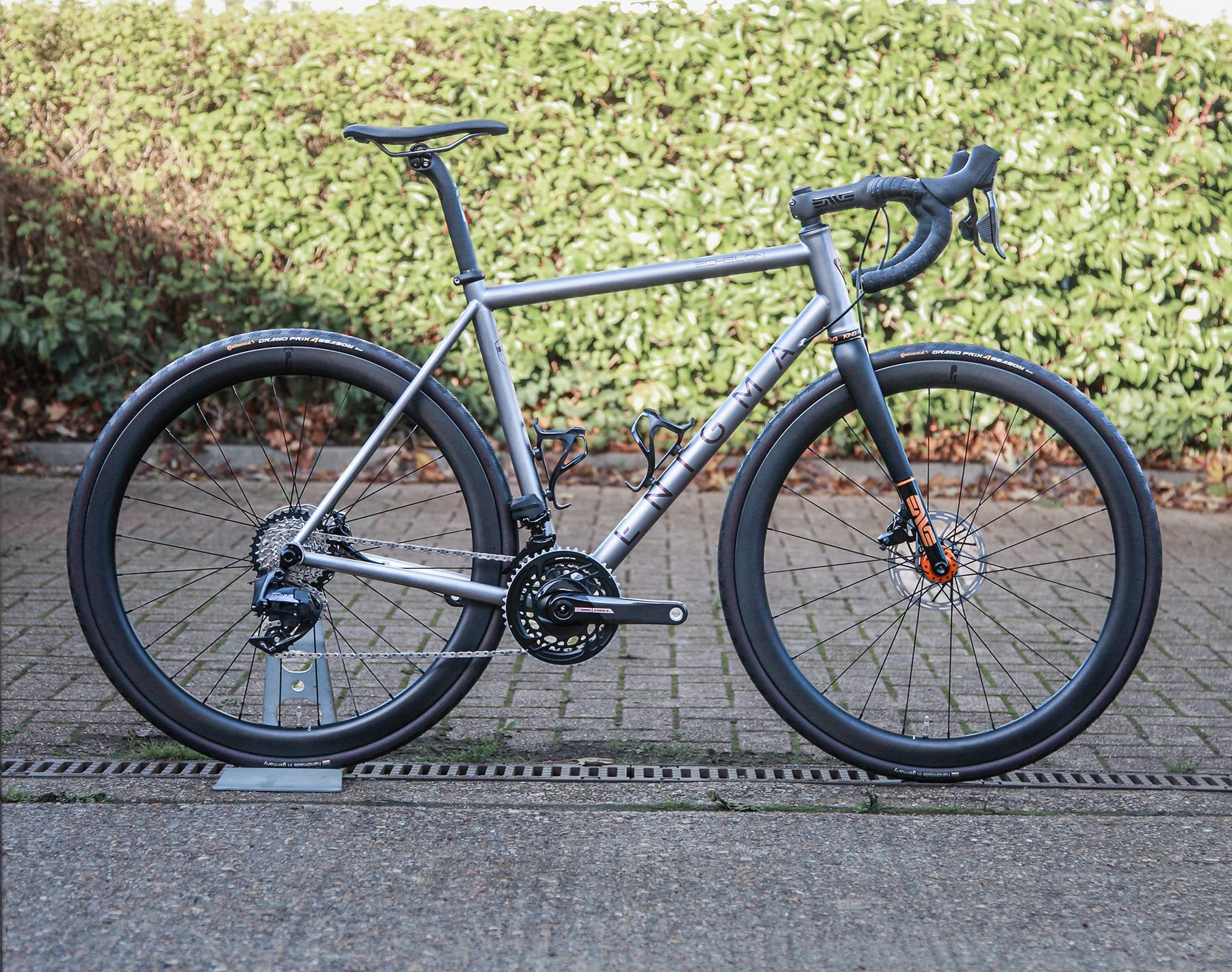 Enigma Echelon Signature 55cm handmade British titanium all-road bike, side profile featuring SRAM Force eTap electronic shifting, handbuilt carbon wheels, ENVE components and custom-painted black and gold carbon fork.