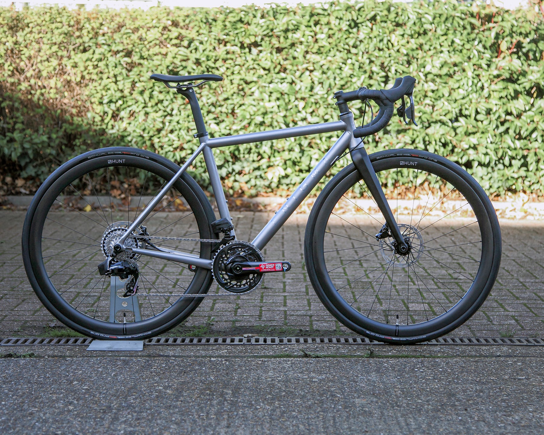 Enigma Elan 52cm titanium road bike with brushed titanium frame, SRAM Force AXS 12-speed electronic groupset, Hunt 40 carbon wheels and black carbon fork, shown in side profile.