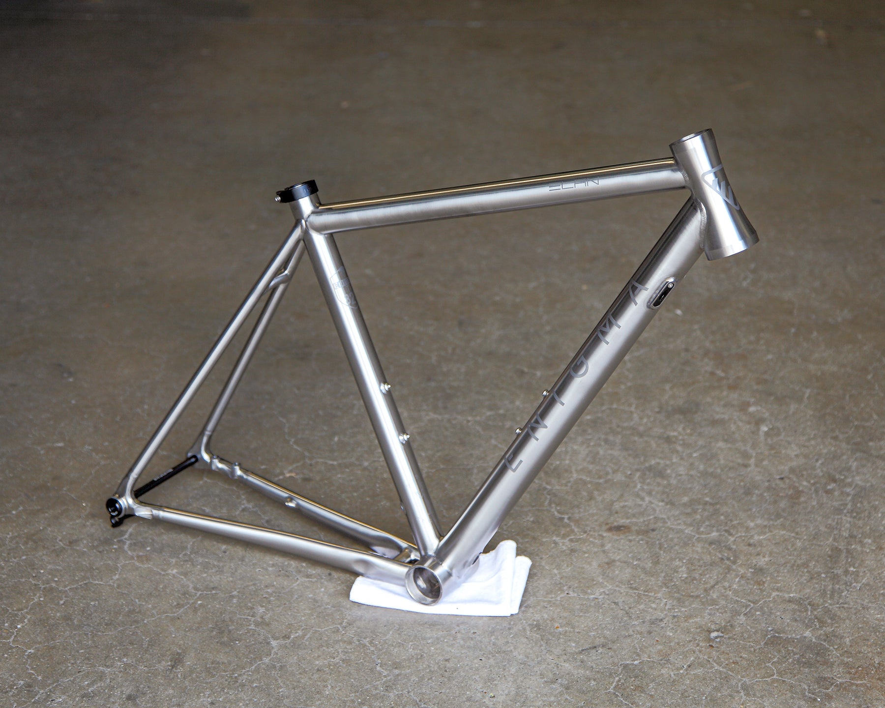 Enigma Elan 50cm UK-handcrafted titanium road frame, three-quarter view showing brushed titanium finish, satin bead logos and traditional road frame design.