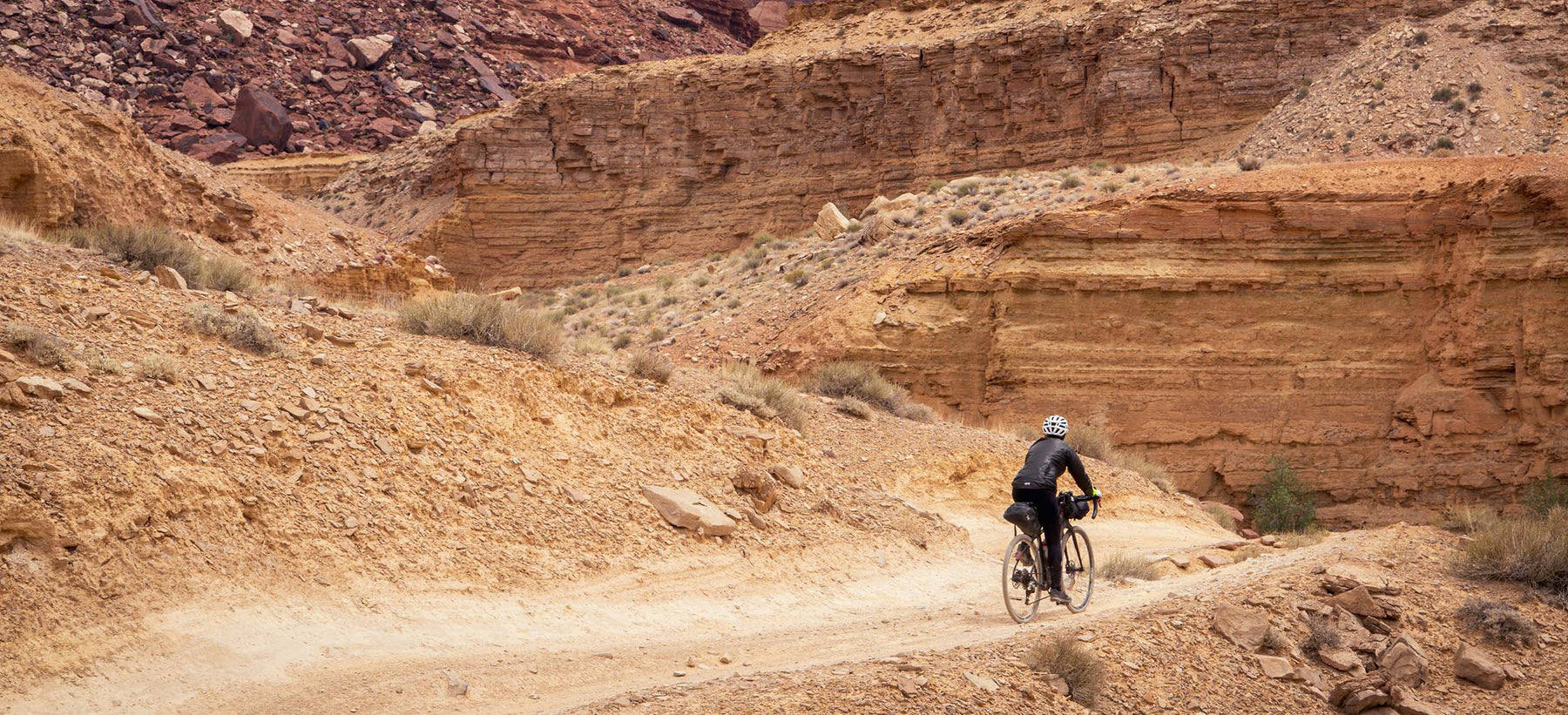 Rider on an Enigma titanium adventure bike riding through a rocky desert canyon.
