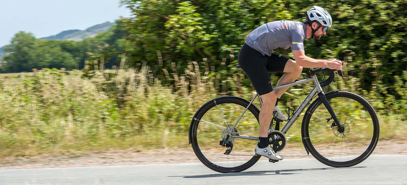 Rider on an Enigma titanium road bike riding along a country lane.