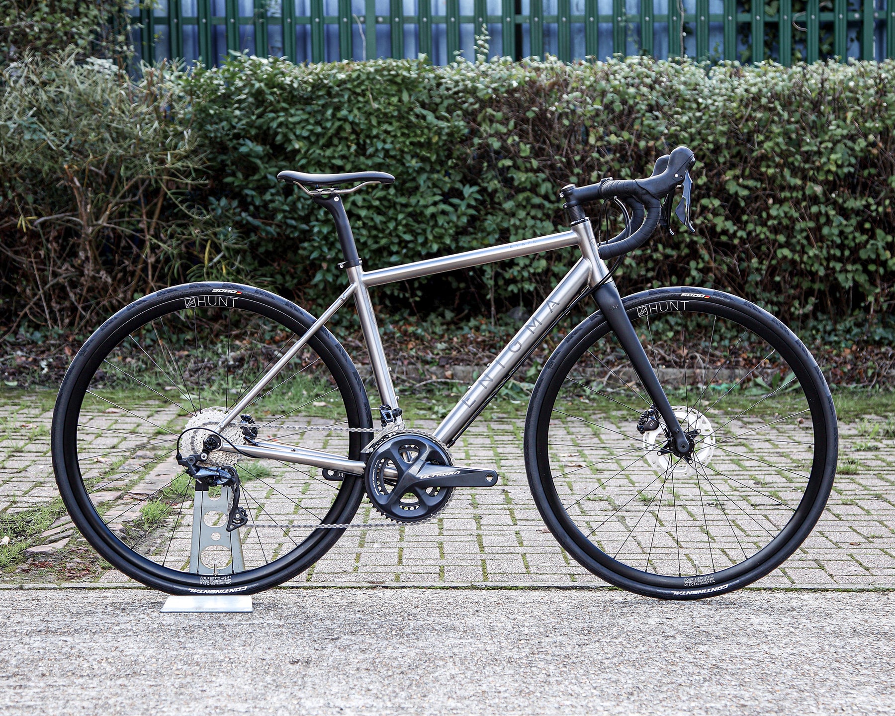 Enigma Etape 52cm titanium all-road bike, side profile showing brushed titanium frame, Shimano Ultegra 11-speed drivetrain, Hunt 4 Season Disc wheels and carbon fork.