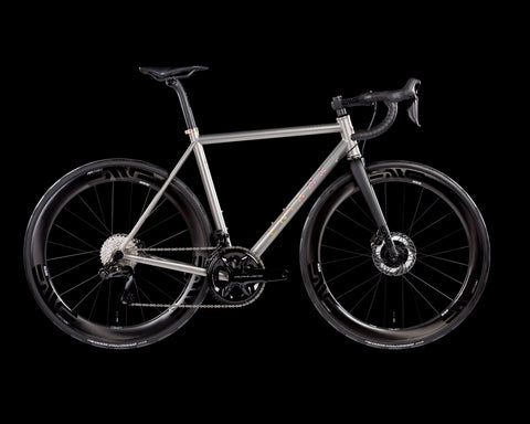 High-performance Excel titanium road bike with aerodynamic carbon wheels, disc brakes, and drop handlebars, designed for speed and endurance cycling.